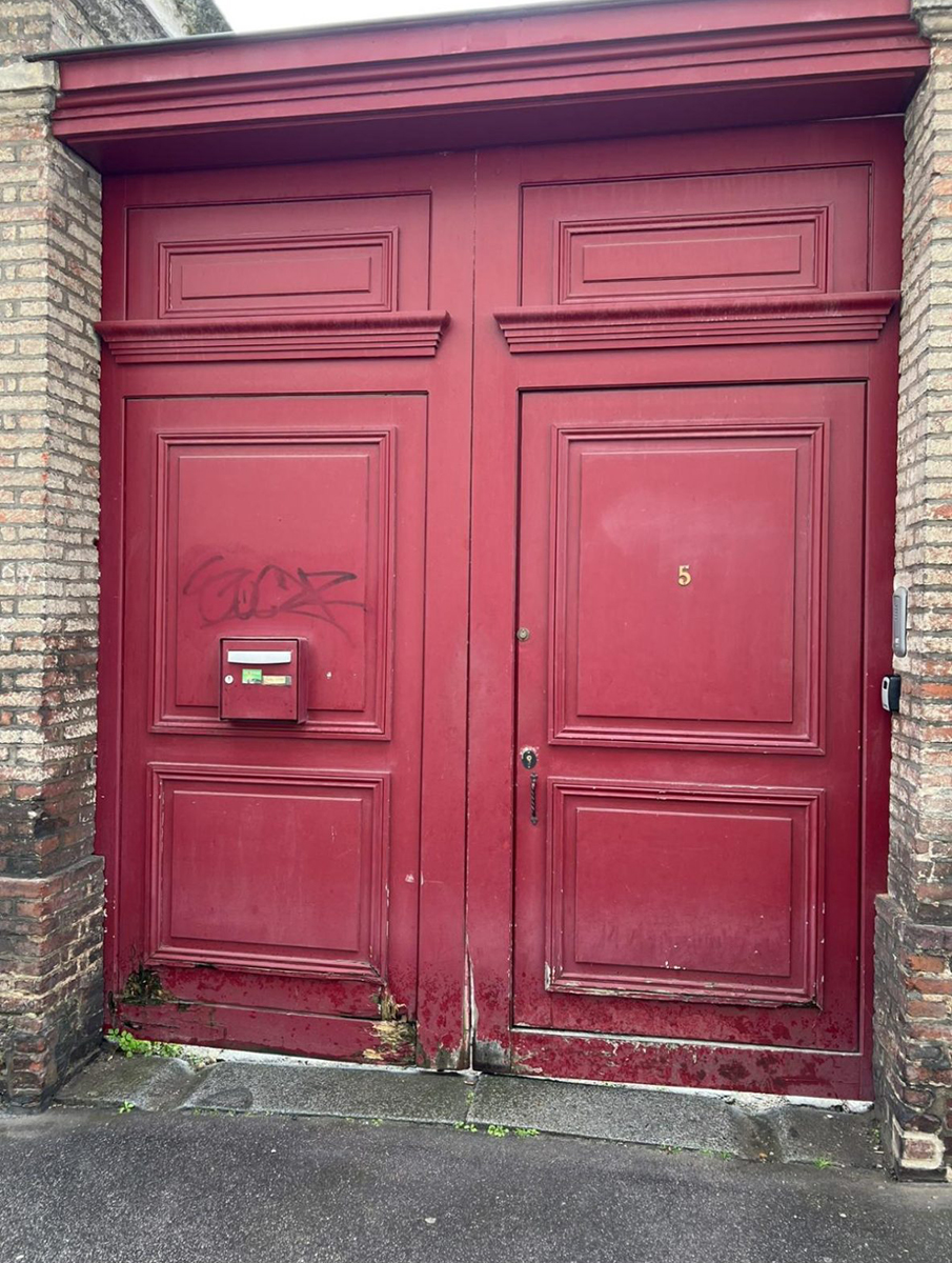 Une porte rouge en bois avec une boîte aux lettres intégrée.